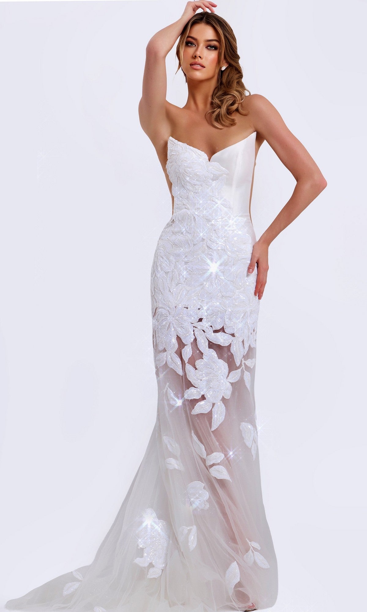A woman wears the Jovani 44437 long prom dress in off white, featuring a strapless design, floral lace details, and a sheer skirt, standing against a plain light background.